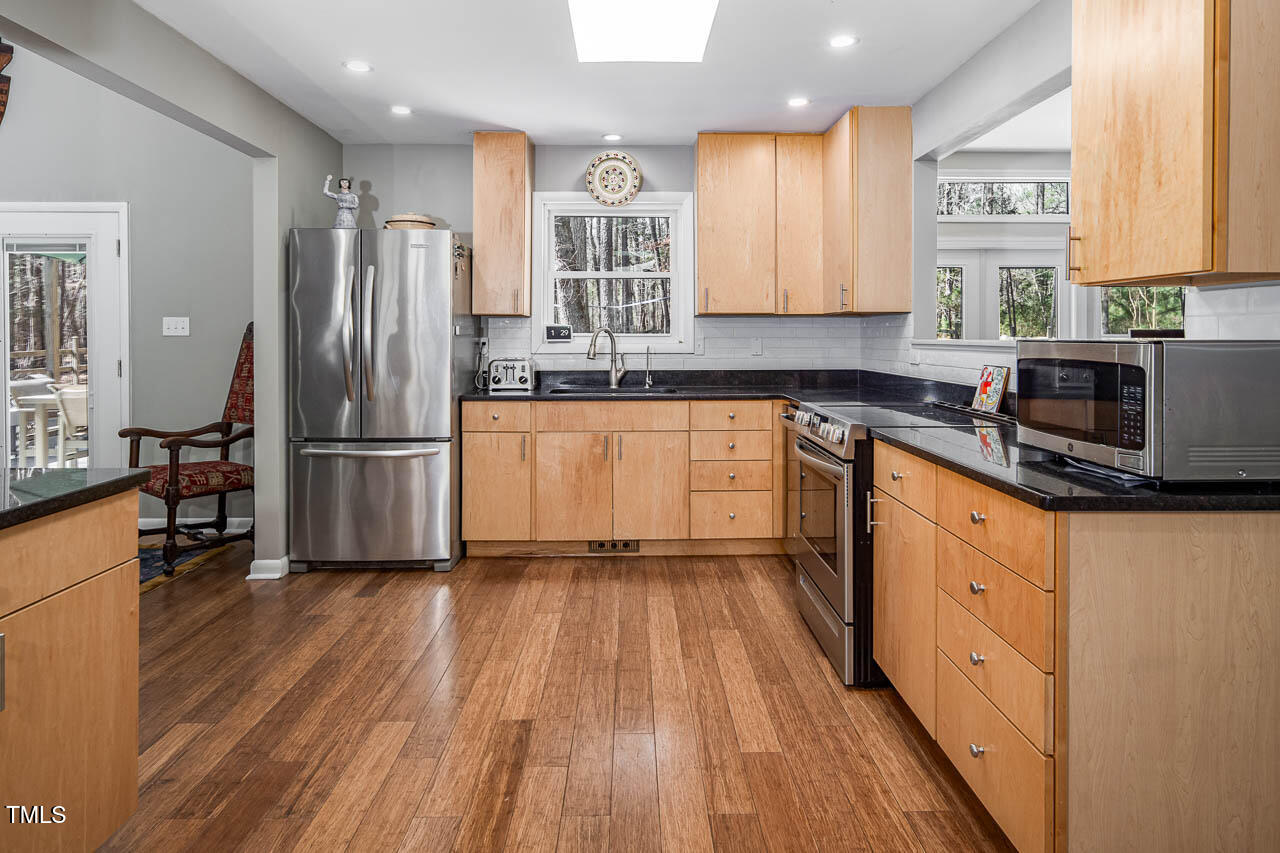 9501 Coachway Chapel Hill, NC 27516 - Photo 10 of 47 a kitchen with granite countertop wooden floors stainless steel appliances a sink and a window