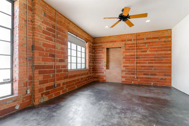 a view of an empty room with brick wall and a window