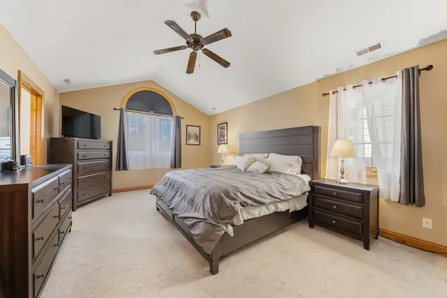 a spacious bedroom with a large bed a flat tv screen and a dresser