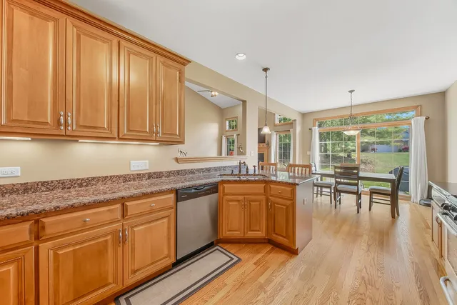 a kitchen with stainless steel appliances granite countertop wooden floors and white cabinets