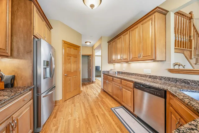 a kitchen with stainless steel appliances granite countertop a refrigerator a stove and a sink with wooden floor