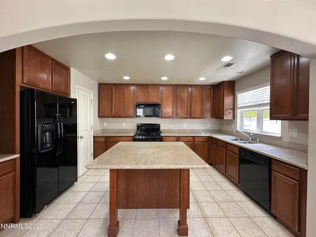 a large kitchen with stainless steel appliances kitchen island granite countertop a refrigerator and a stove top oven