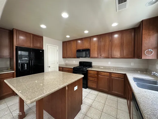 a kitchen with stainless steel appliances granite countertop a sink dishwasher stove top oven and wooden cabinets