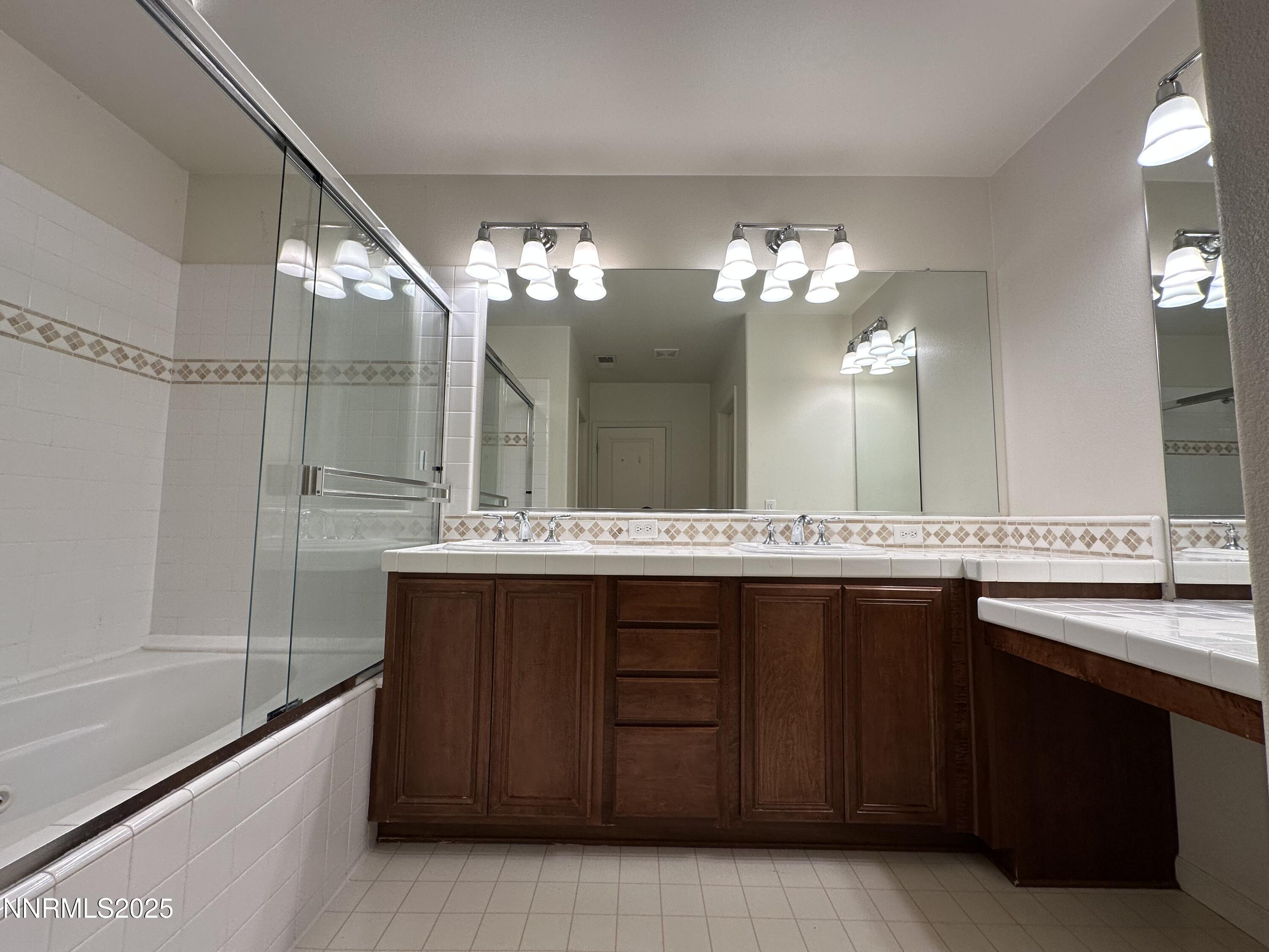 1625 Clover Hill Trail Reno, NV 89523 - Photo 22 of 41 a bathroom with a granite countertop sink a large mirror and a bathtub