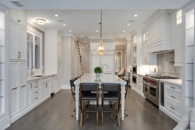 a kitchen with stainless steel appliances granite countertop a stove top oven a refrigerator a sink and a dining table with wooden floor