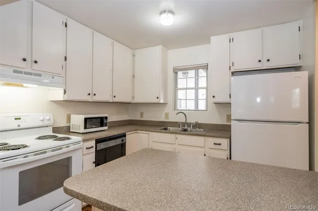a kitchen with granite countertop white cabinets and white appliances