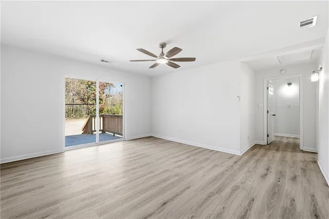 an empty room with wooden floor and a ceiling fan