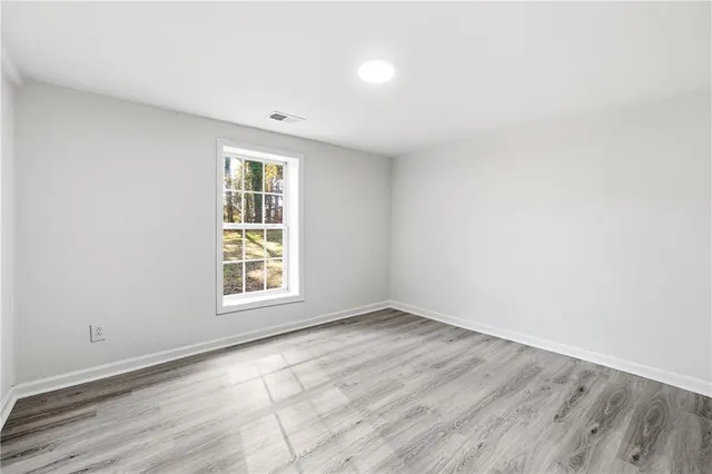 an empty room with wooden floor and windows