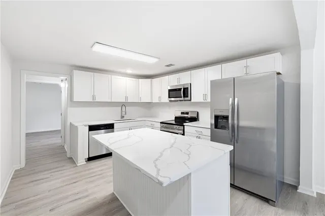 a kitchen that has a refrigerator a stove and white cabinets with wooden floor