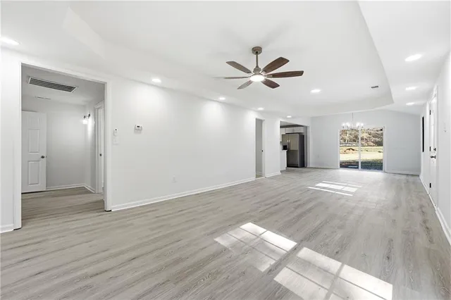 a view of a livingroom with a ceiling fan wooden floor and a ceiling fan