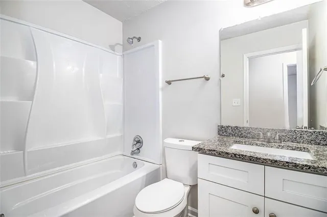 a bathroom with a granite countertop tub sink toilet and mirror
