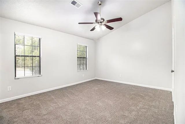 an empty room with windows and fan