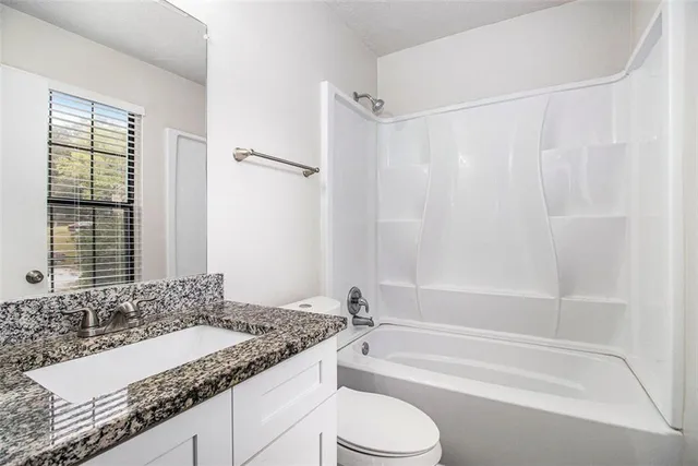 a bathroom with a granite countertop sink and a bathtub
