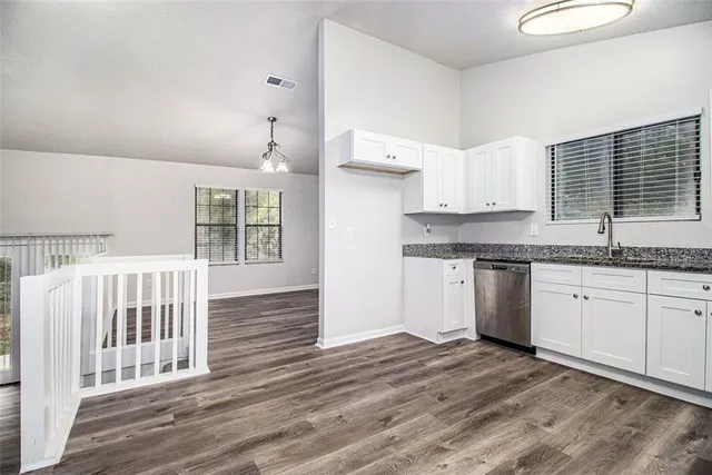 a kitchen with granite countertop a sink cabinets stainless steel appliances and a window