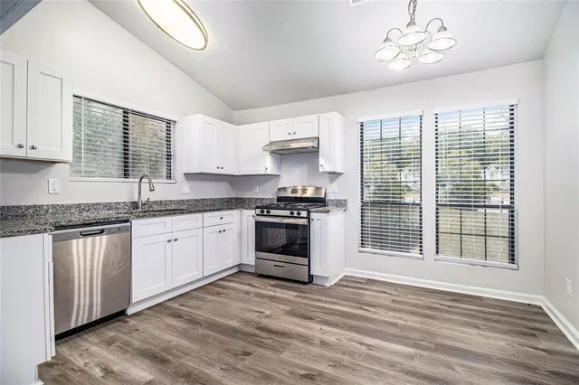 a kitchen with granite countertop a stove a sink and a microwave