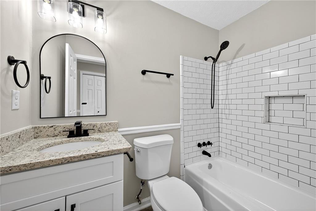 187 Old Timber Road Lawrenceville, GA 30046 - Photo 24 of 32 a bathroom with a granite countertop toilet a sink and a bathtub