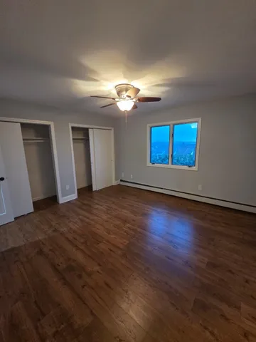 a view of an empty room with window and wooden floor