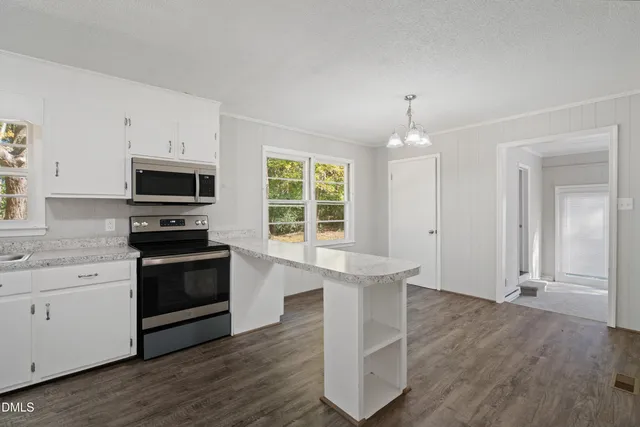 an empty room with wooden floor chandelier fan and windows