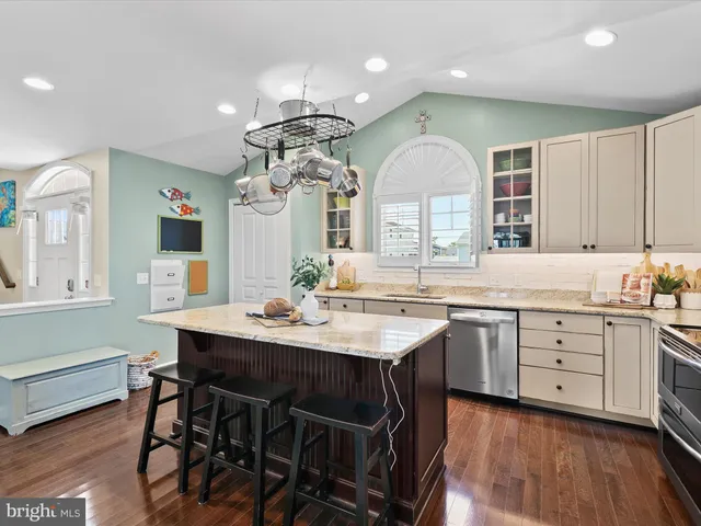a view of a dining room and livingroom with furniture wooden floor a rug a painting and a chandelier