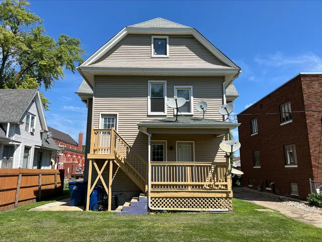 a view of a house with a barbeque and wooden stairs