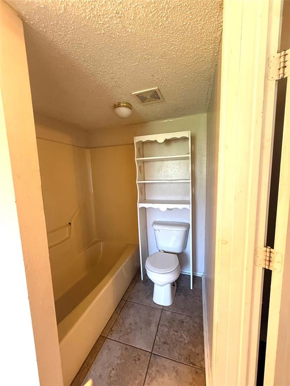 217 3rd St Pinehill Springhill, LA 71075 - Photo 9 of 23 Bathroom featuring a built-in tub, white toilet, and neutral-toned floor tiles