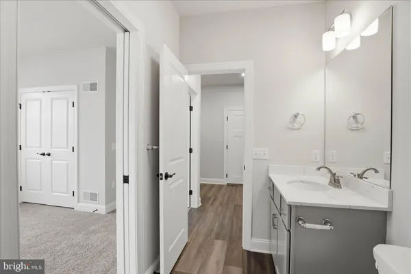 a large white kitchen with granite countertop a stove a sink a dining table and chairs with wooden floor