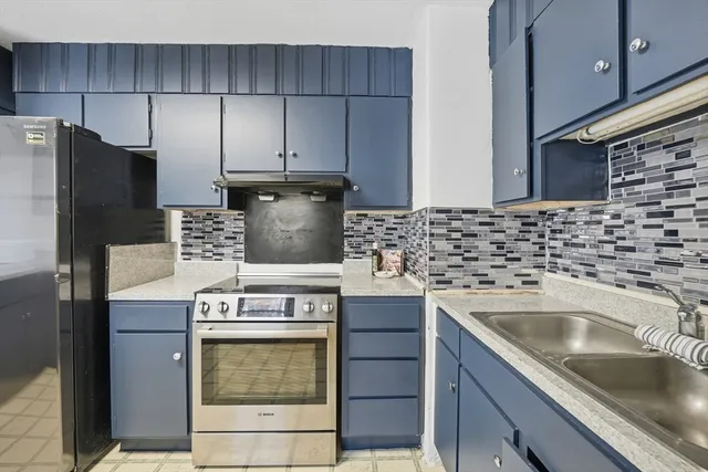 a kitchen with granite countertop a sink stove and refrigerator