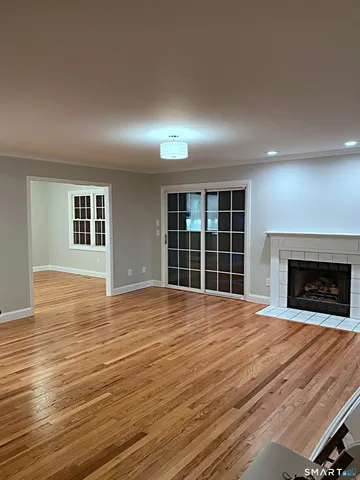 a view of an empty room with wooden floor and a fireplace