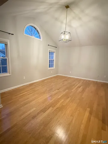 a view of an empty room with a window and wooden floor