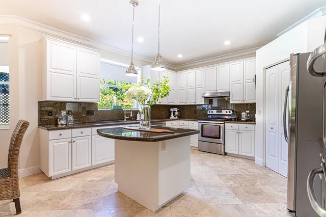 a kitchen with stainless steel appliances granite countertop a stove a sink a refrigerator a center island a stove and cabinets