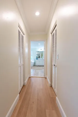 a view of a hallway with wooden floor and a bathroom
