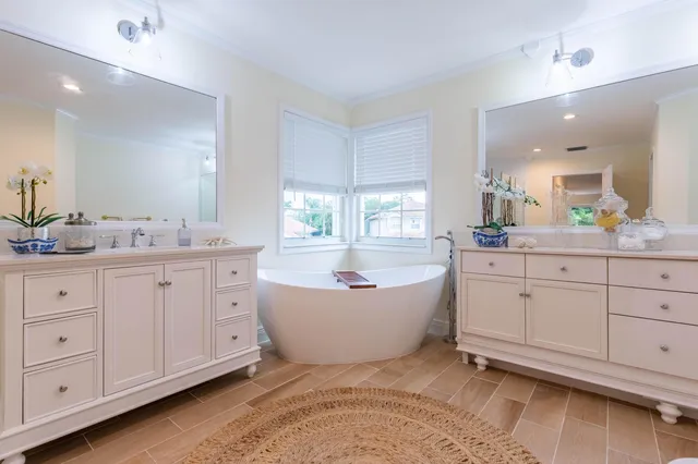 a spacious bathroom with double sink a a bathtub a mirror a vanity and window