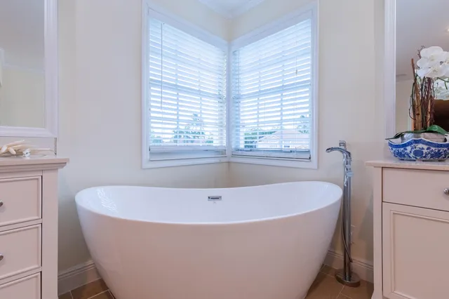 a white bath tub sitting in a bathroom next to a window