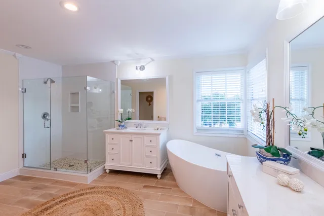 a spacious bathroom with a tub sink shower and a mirror