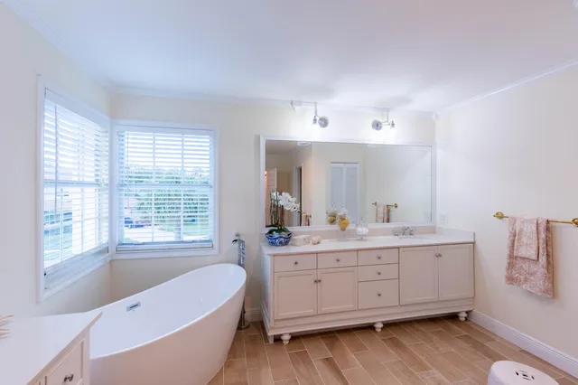 a bathroom with a double vanity sink a large mirror and a bathtub