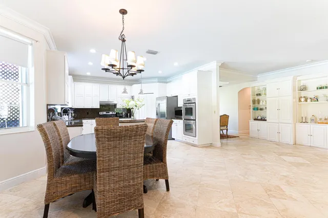 a dining room with furniture a chandelier and kitchen view