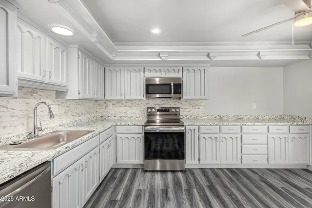 a kitchen with granite countertop a sink stove and microwave
