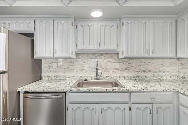 a kitchen with granite countertop a sink a stove and cabinets
