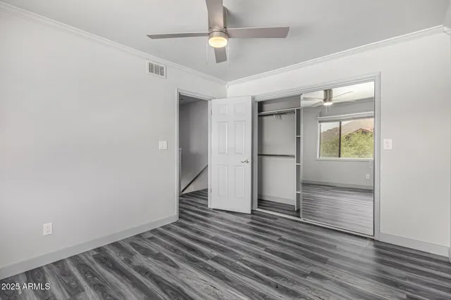 an empty room with wooden floor cabinet and windows