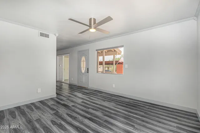 a view of an empty room with wooden floor and a window