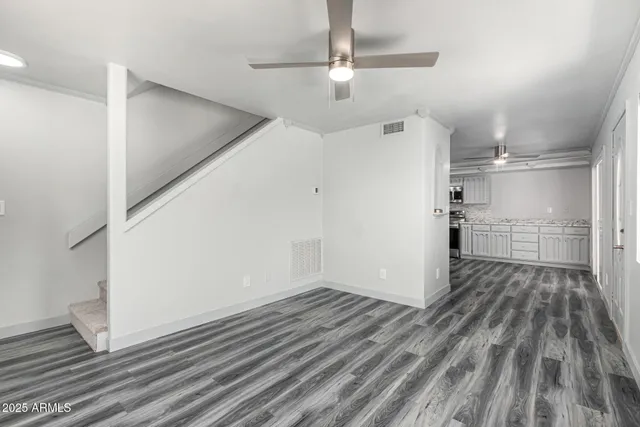 a view of a hallway with wooden floor and a refrigerator