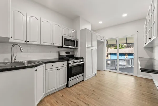 a kitchen with stainless steel appliances granite countertop a stove a sink and a microwave