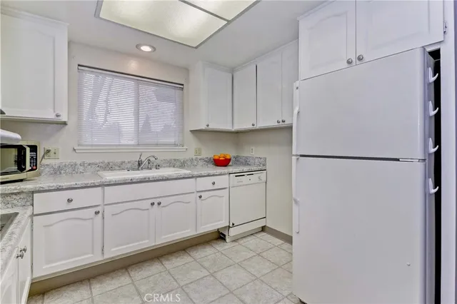 a kitchen with granite countertop cabinets sink and a refrigerator