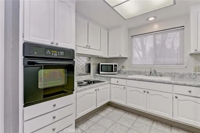 a kitchen with granite countertop white cabinets and white appliances