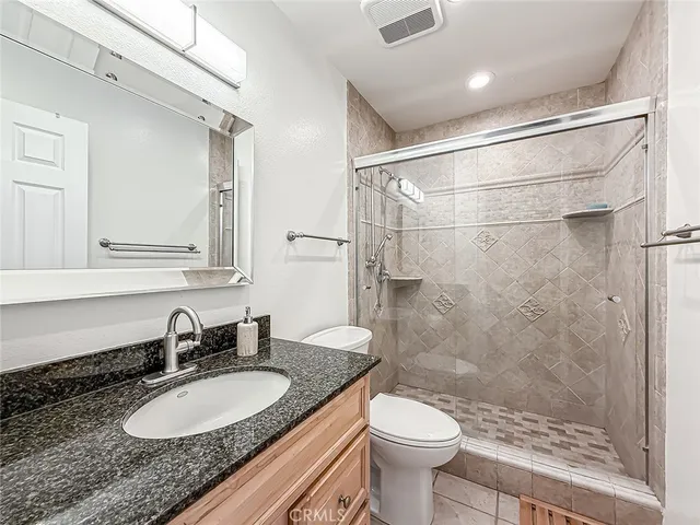 a bathroom with a granite countertop sink toilet a mirror and shower