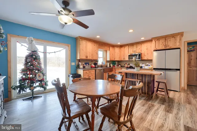 a kitchen with stainless steel appliances granite countertop a stove top oven a sink dishwasher a dining table and chairs with wooden floor