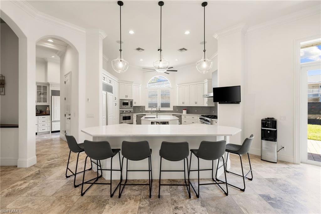 185 Tupelo Road Naples, FL 34108 - Photo 13 of 44 a kitchen with stainless steel appliances kitchen island granite countertop a table and chairs in it