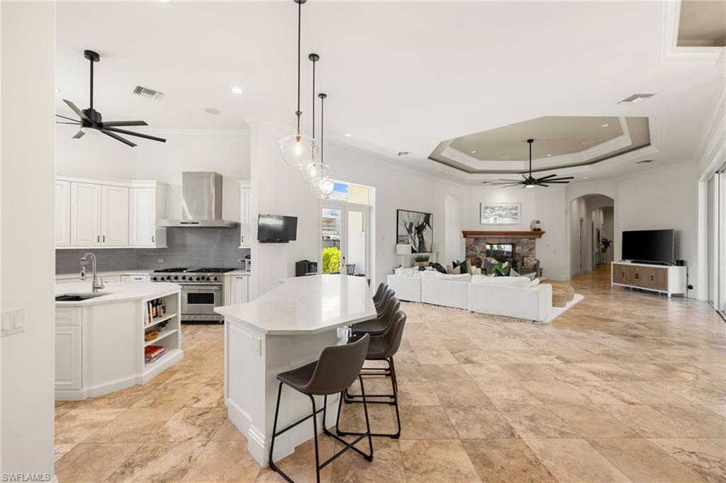 185 Tupelo Road Naples, FL 34108 - Photo 16 of 44 a kitchen with kitchen island a stove a table a sink a counter top space and cabinets