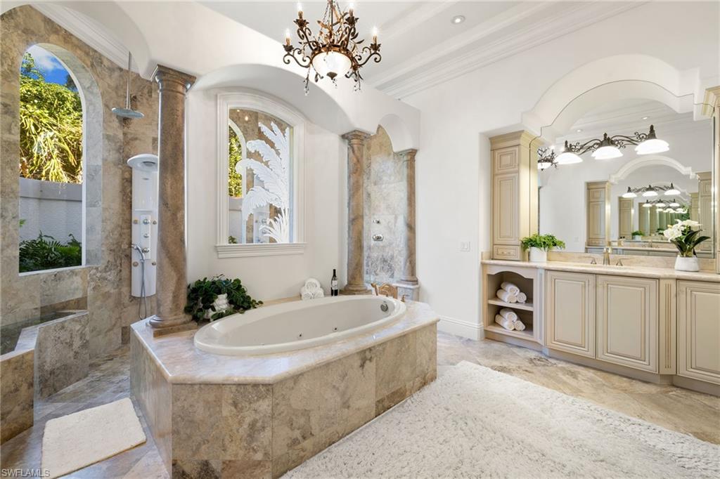 185 Tupelo Road Naples, FL 34108 - Photo 22 of 44 a spacious bathroom with a granite countertop tub a double vanity sink and a mirror