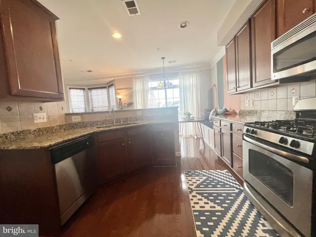 a kitchen with granite countertop a stove a sink and a microwave